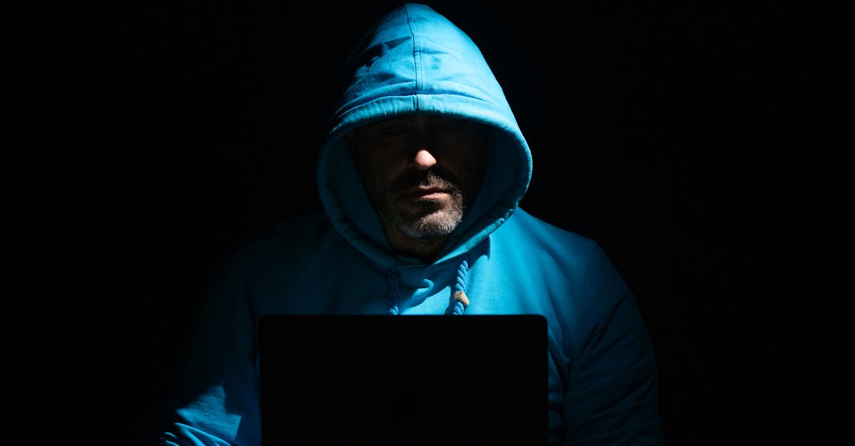 Homem focado trabalhando no laptop em quarto escuro